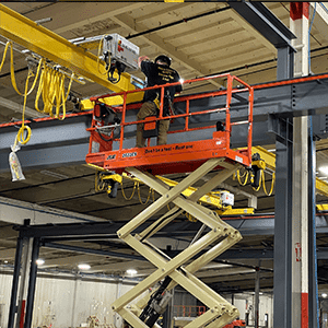 A Service Crane Company employee performing an installation from a scissor lift